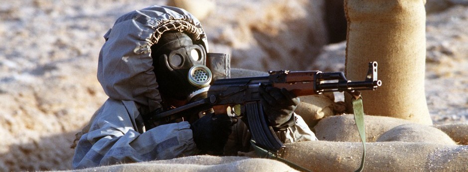 Syrian soldier wearing chemical warfare mask aims AK47